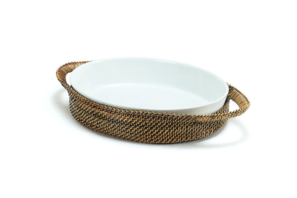 Handwoven Calaisio oval basket holding a Pillivuyt 2-quart porcelain baker with vegetables served on a wooden dining table.