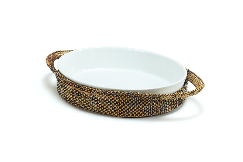 Handwoven Calaisio oval basket holding a Pillivuyt 2-quart porcelain baker with vegetables served on a wooden dining table.