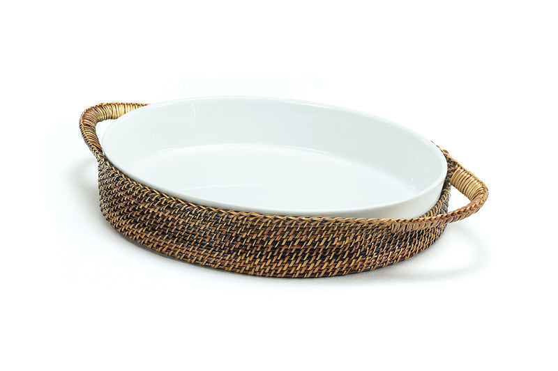 Calaisio handwoven oval casserole basket holding Pillivuyt 3-quart porcelain baker filled with food on a set dining table.