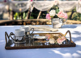 Tea set with flowers on a tray with glass on a table outdoors