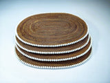 Stack of brown woven placemats with white edges on a light blue background