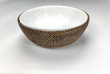 White ceramic bowl with woven brown rim on a white background