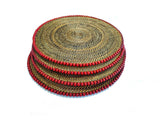 Set of round woven placemats with red trim on a white background