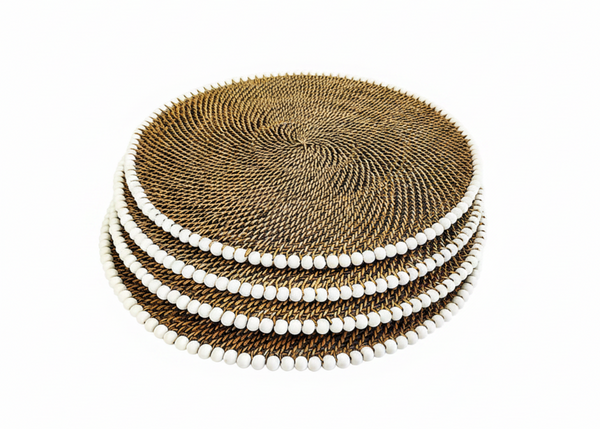 A stack of round woven placemats in a natural brown tone, each bordered with a row of small white beads, photographed on a plain white background.