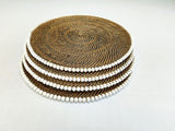 Set of round woven placemats with a white and brown color scheme on a light gray background.